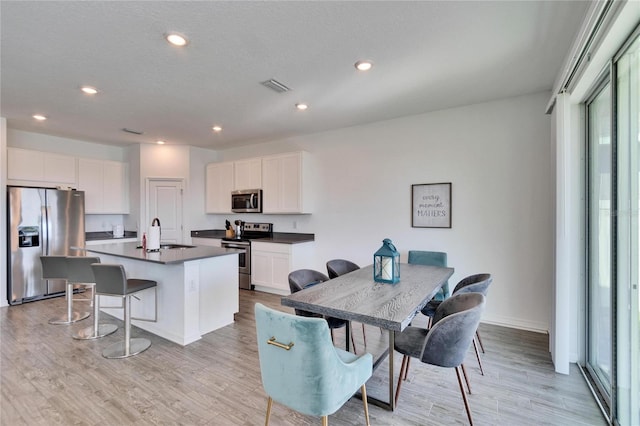 kitchen with appliances with stainless steel finishes, dark countertops, light wood-style flooring, and visible vents