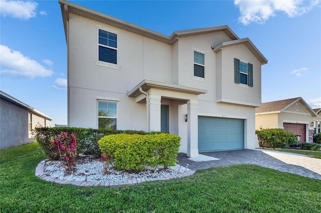 view of front of property with a garage, a front yard, decorative driveway, and stucco siding