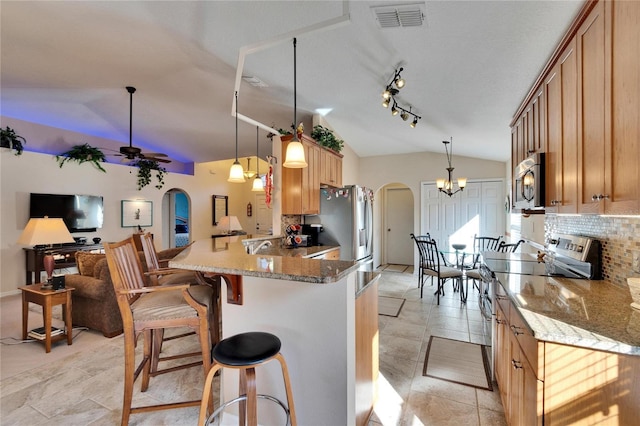 kitchen featuring lofted ceiling, hanging light fixtures, stainless steel appliances, decorative backsplash, and kitchen peninsula