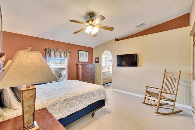 bedroom with connected bathroom, vaulted ceiling, and light colored carpet