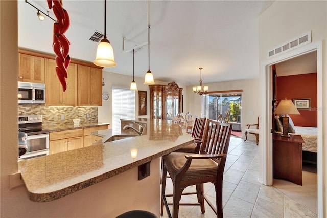 kitchen featuring sink, tasteful backsplash, decorative light fixtures, appliances with stainless steel finishes, and a notable chandelier