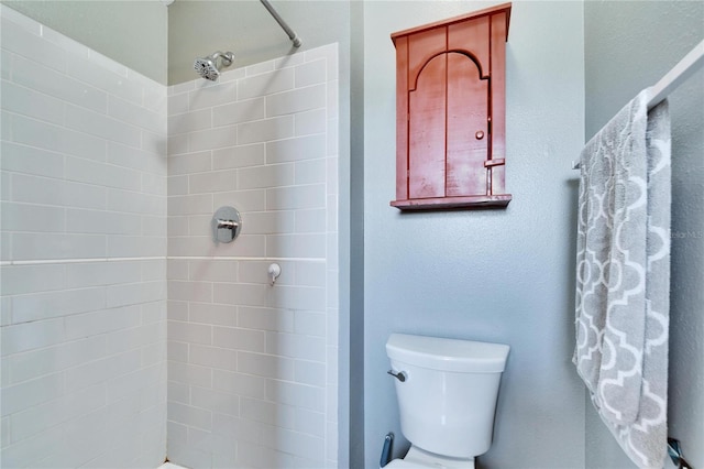 bathroom featuring tiled shower and toilet