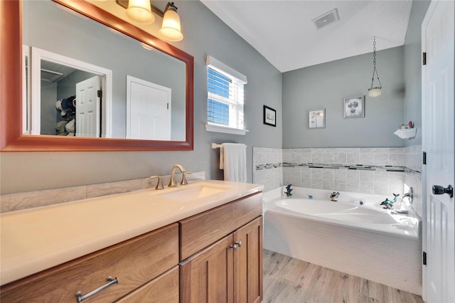 bathroom with vanity, wood-type flooring, and tiled bath