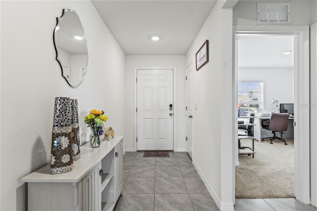 entryway with light colored carpet, visible vents, baseboards, and light tile patterned flooring