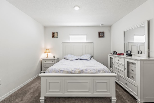 bedroom with dark carpet, a textured ceiling, and baseboards