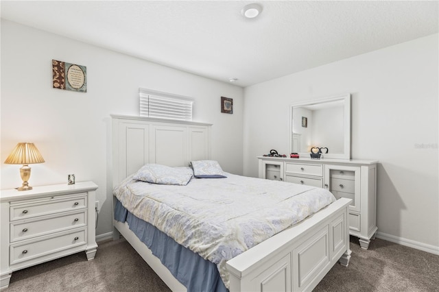 bedroom with dark carpet and baseboards