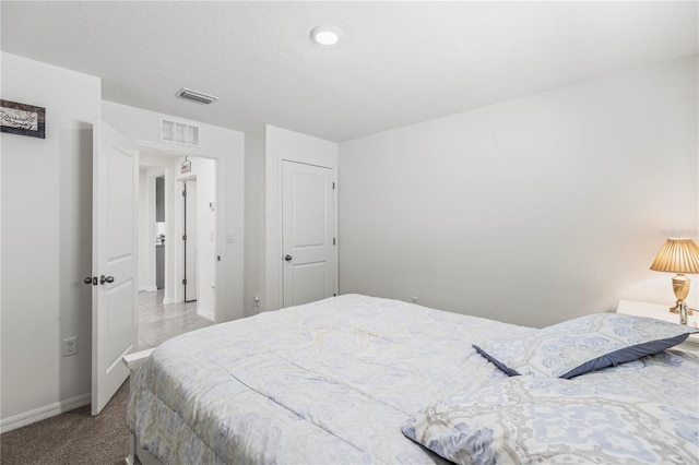 bedroom with baseboards, visible vents, a textured ceiling, and light colored carpet