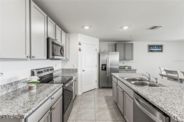 kitchen with a center island with sink, stainless steel appliances, visible vents, light tile patterned flooring, and a sink