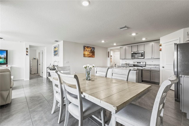 tiled dining space with recessed lighting, visible vents, and a textured ceiling