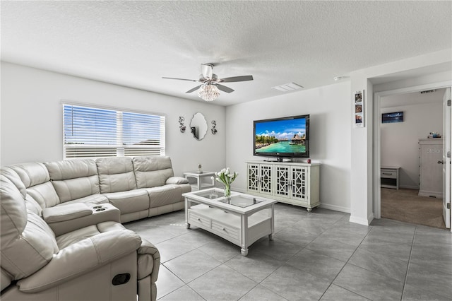 living area with light tile patterned floors, visible vents, a ceiling fan, a textured ceiling, and baseboards