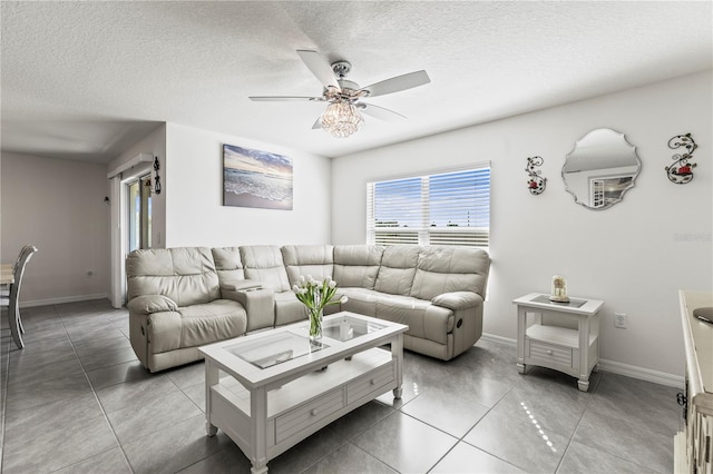 tiled living room featuring a ceiling fan, a textured ceiling, and baseboards