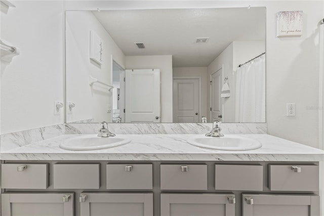 bathroom featuring visible vents, a sink, a shower with shower curtain, and double vanity