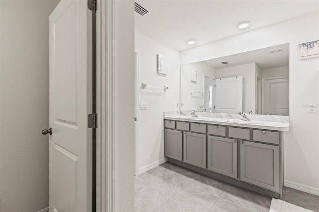 bathroom featuring double vanity, a sink, and baseboards