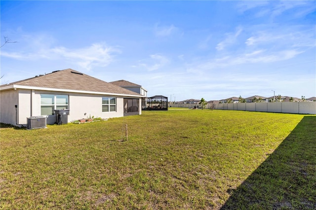 view of yard with central AC and fence