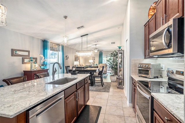 kitchen with sink, appliances with stainless steel finishes, a kitchen island with sink, hanging light fixtures, and plenty of natural light