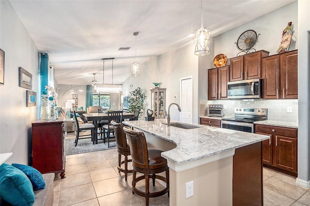 kitchen featuring pendant lighting, sink, a breakfast bar area, stainless steel appliances, and a center island with sink