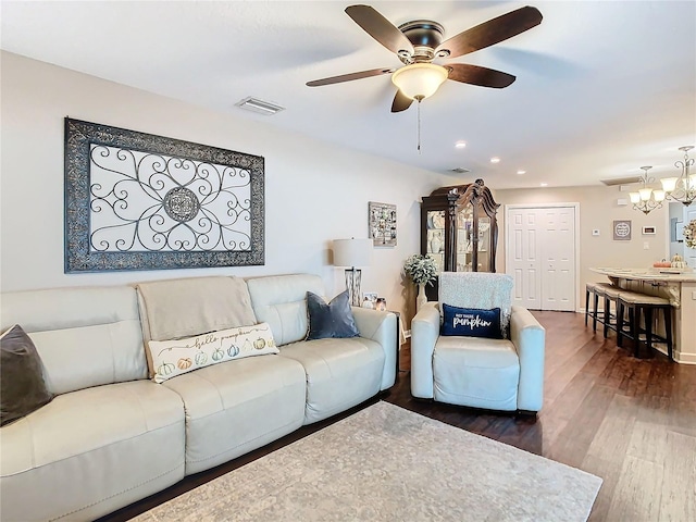 living room featuring ceiling fan with notable chandelier and dark hardwood / wood-style floors