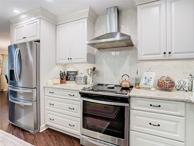 kitchen featuring tasteful backsplash, white cabinets, stainless steel appliances, and wall chimney range hood