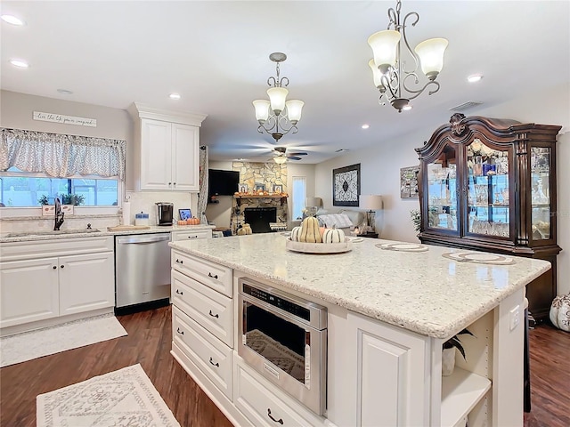 kitchen with pendant lighting, sink, white cabinetry, stainless steel appliances, and a kitchen island