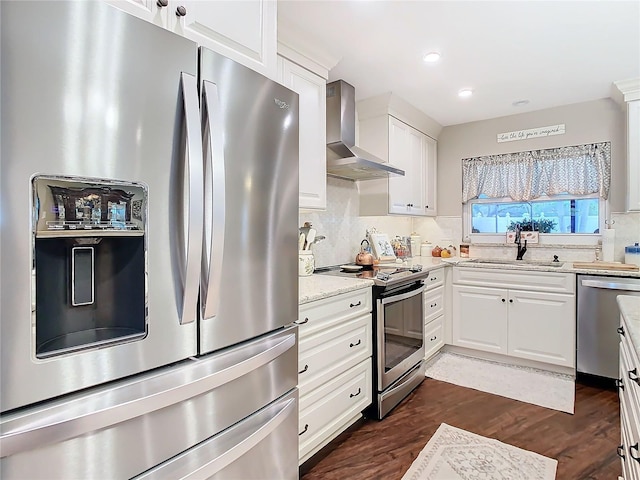 kitchen featuring sink, white cabinetry, stainless steel appliances, light stone counters, and wall chimney exhaust hood