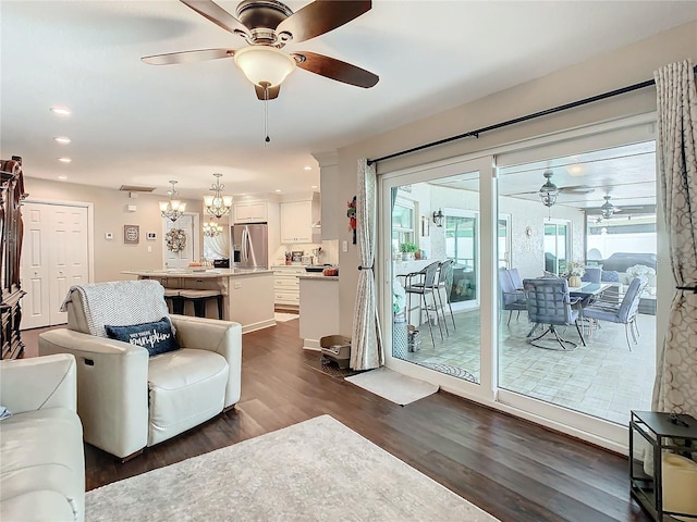 living room with dark hardwood / wood-style flooring and ceiling fan with notable chandelier