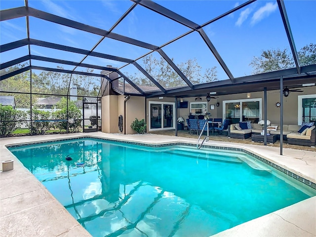 view of pool with ceiling fan, outdoor lounge area, glass enclosure, and a patio area