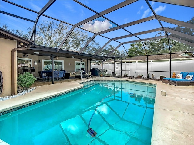 view of swimming pool featuring a patio area, ceiling fan, and glass enclosure