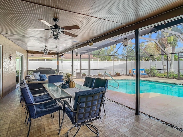 view of swimming pool with ceiling fan, a patio, outdoor lounge area, and glass enclosure