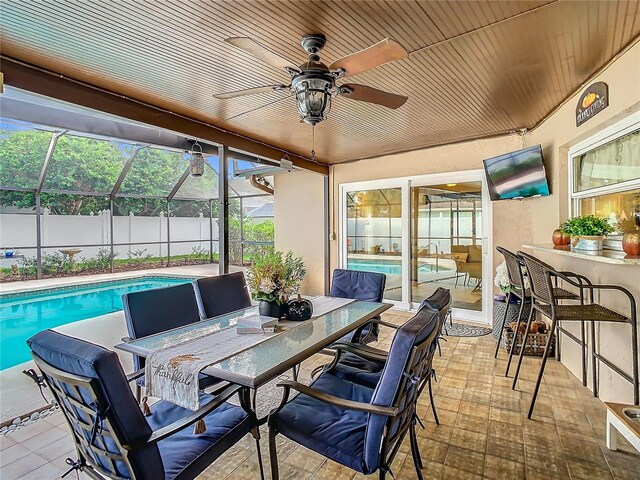 view of patio featuring a fenced in pool, a lanai, exterior bar, and ceiling fan