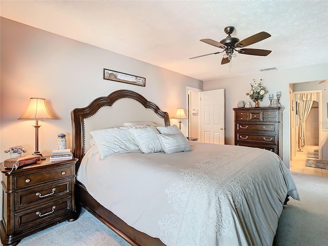 bedroom featuring light carpet, ceiling fan, and ensuite bathroom