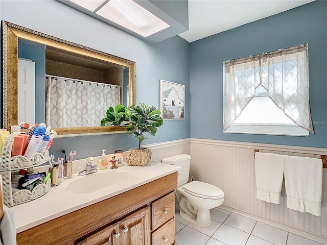 bathroom featuring vanity, a skylight, tile patterned floors, and toilet