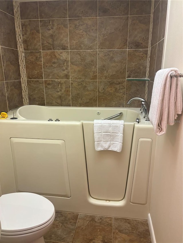 bathroom with a tub to relax in, toilet, and tile patterned flooring