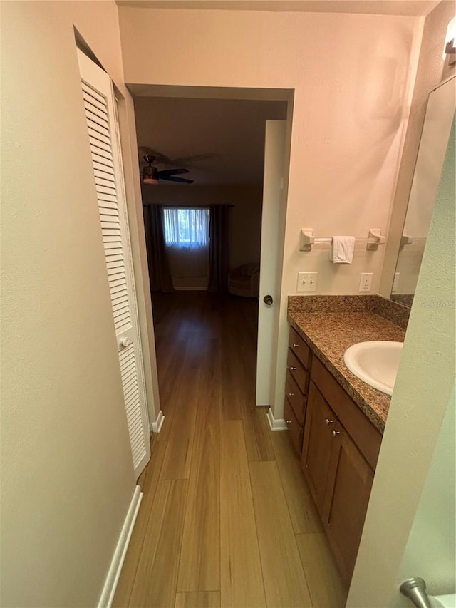 bathroom with ceiling fan, vanity, and wood-type flooring