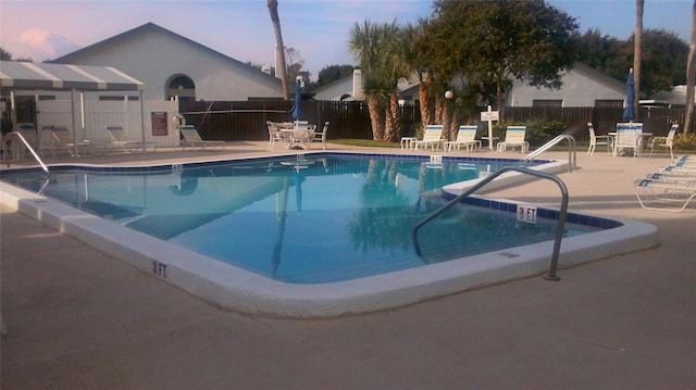 pool at dusk featuring a patio