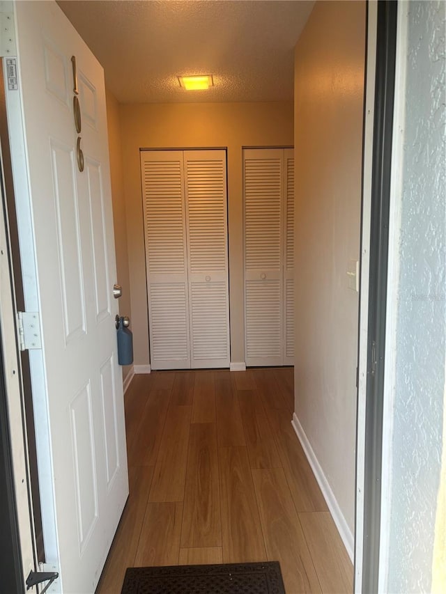 corridor featuring hardwood / wood-style flooring and a textured ceiling