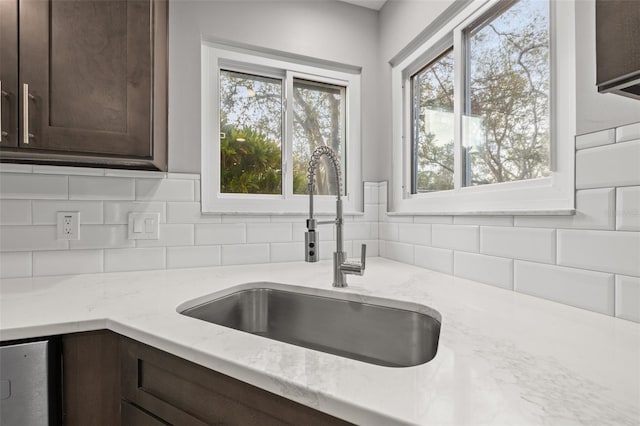 kitchen featuring dark brown cabinetry, light stone countertops, and sink