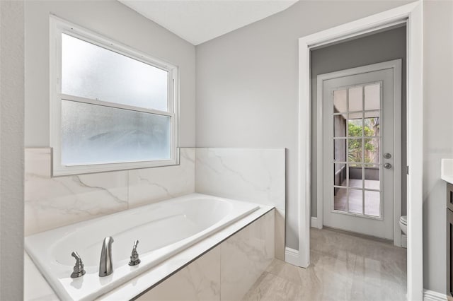 bathroom featuring toilet, vanity, and tiled bath