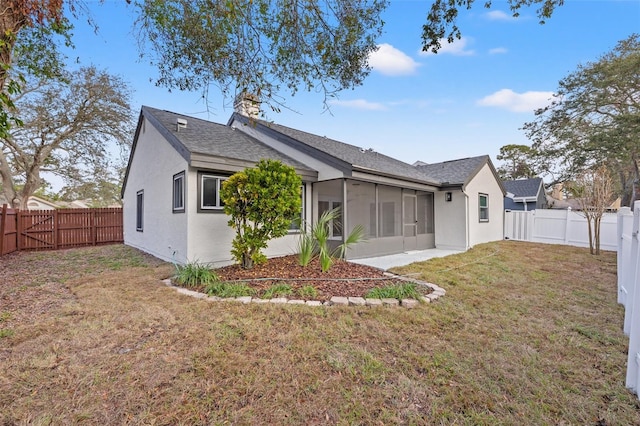 back of house featuring a yard and a sunroom