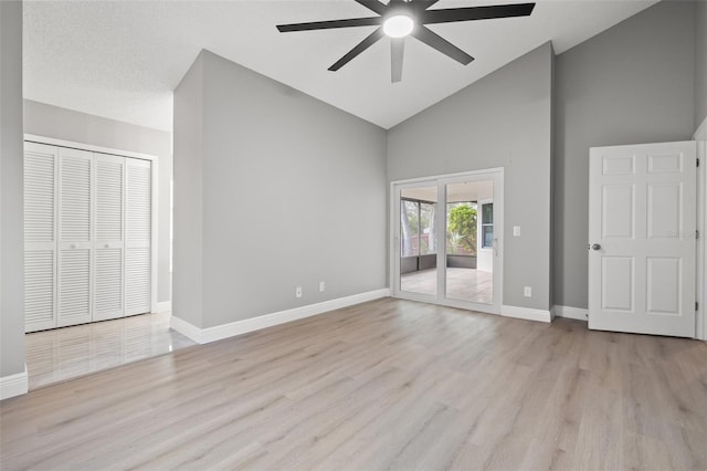 unfurnished bedroom with high vaulted ceiling, access to exterior, and light hardwood / wood-style floors