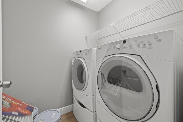 clothes washing area featuring wood-type flooring and separate washer and dryer