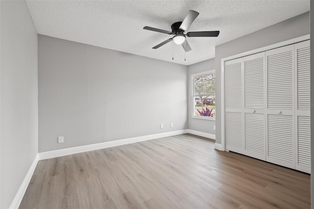 unfurnished bedroom featuring ceiling fan, a closet, a textured ceiling, and light wood-type flooring