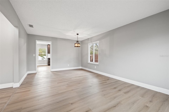 spare room with a textured ceiling and light wood-type flooring