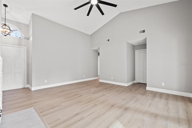 unfurnished living room with ceiling fan with notable chandelier, light hardwood / wood-style flooring, and high vaulted ceiling