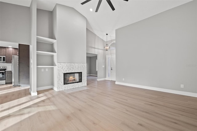 unfurnished living room with ceiling fan, high vaulted ceiling, and light wood-type flooring