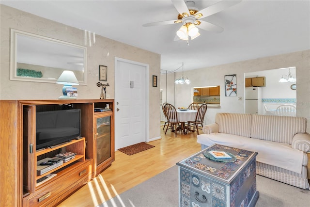 living room with ceiling fan with notable chandelier and hardwood / wood-style floors