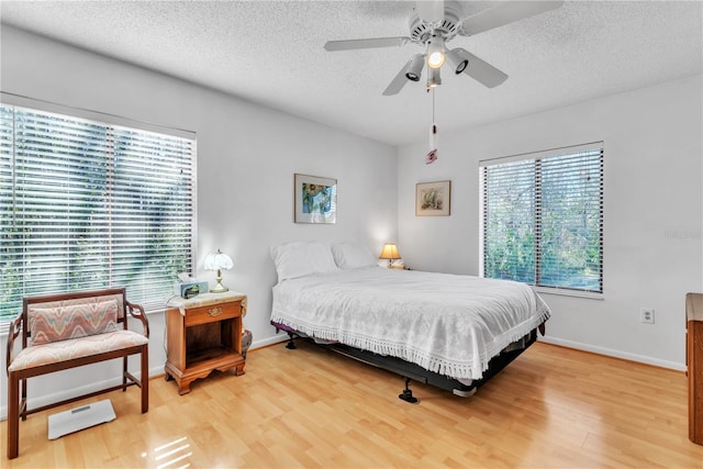 bedroom featuring multiple windows, ceiling fan, hardwood / wood-style floors, and a textured ceiling