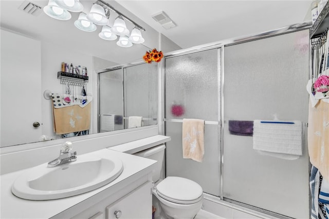 bathroom with a shower with door, vanity, and toilet