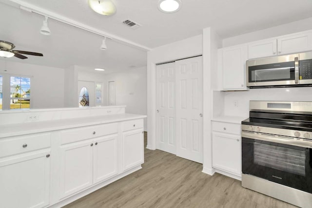 kitchen featuring ceiling fan, stainless steel appliances, light wood-type flooring, and white cabinets