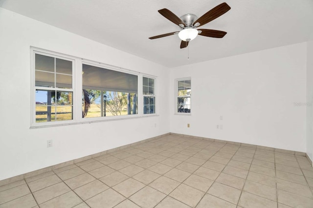 spare room with ceiling fan and light tile patterned floors