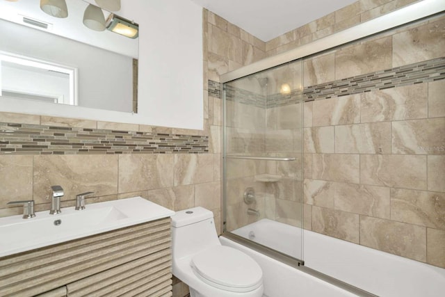 full bathroom with enclosed tub / shower combo, sink, tile walls, and toilet